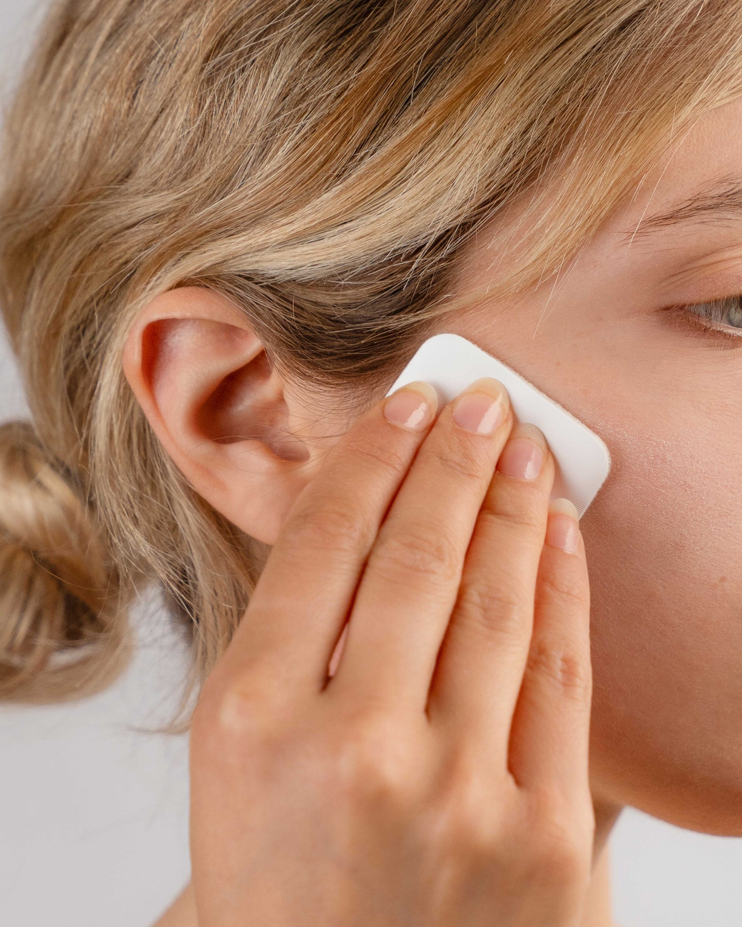 Giovane ragazza applica The Halo, la cipria in gel di DF18+ 3 in 1: primer, base trucco e fissante.