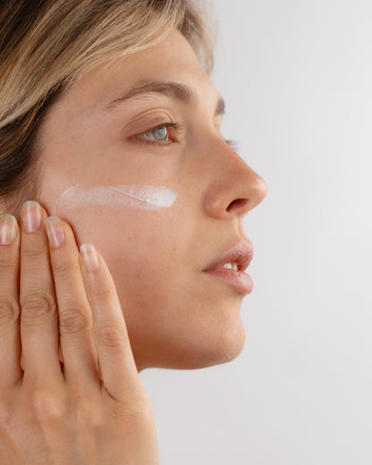Foto di una giovane donna che applica The Intensive, la crema viso antirughe e nutriente di DF18+. 